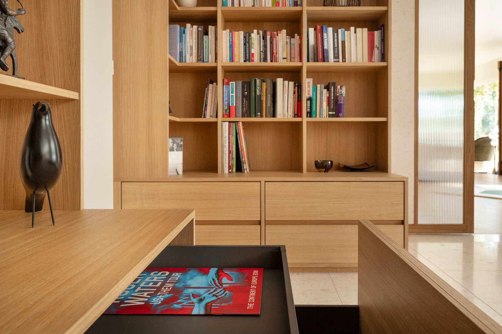 Étagères sur mesure en placage chêne intégrées à une bibliothèque contemporaine.
