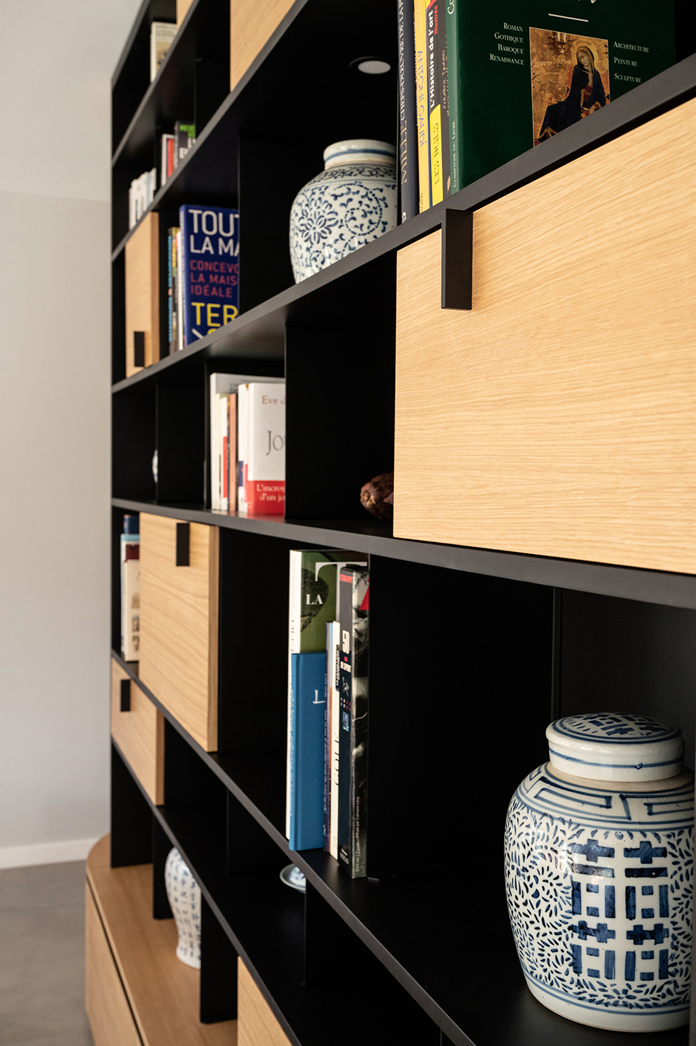 Tiroirs, coffres et rangements intégrés dans une bibliothèque sur mesure fabriquée par l'atelier Guillaume Bouvet.